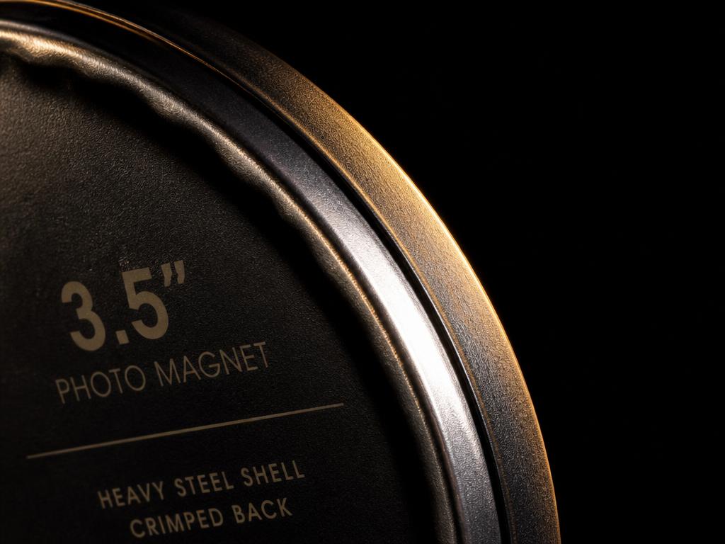 Macro close-up of the heavy metal shell edge and crimped back on a 3.5 inch TSO custom photo magnet